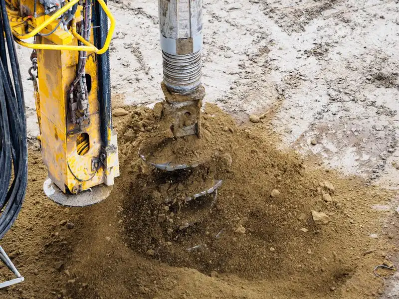 Auger drilling into soil at a borewell site